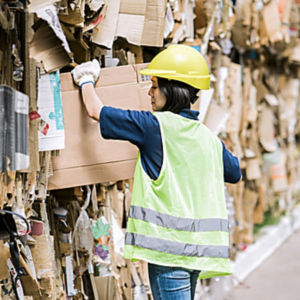 a woman wearing a safety vest and yellow helmet looking at cardboard boxes