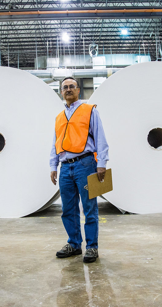 a man standing in front of large rolls of paper