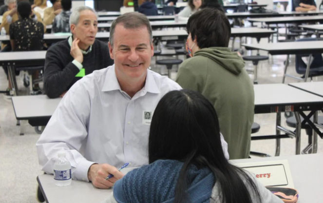 a man sitting at a table with a woman in the background