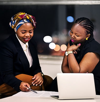 a couple of women looking at a laptop