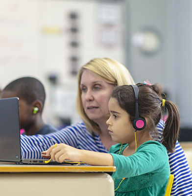 a woman and a girl using a laptop