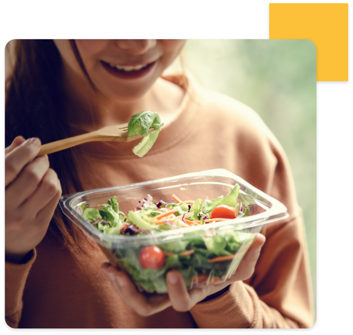 Woman eating salad with wooden fork