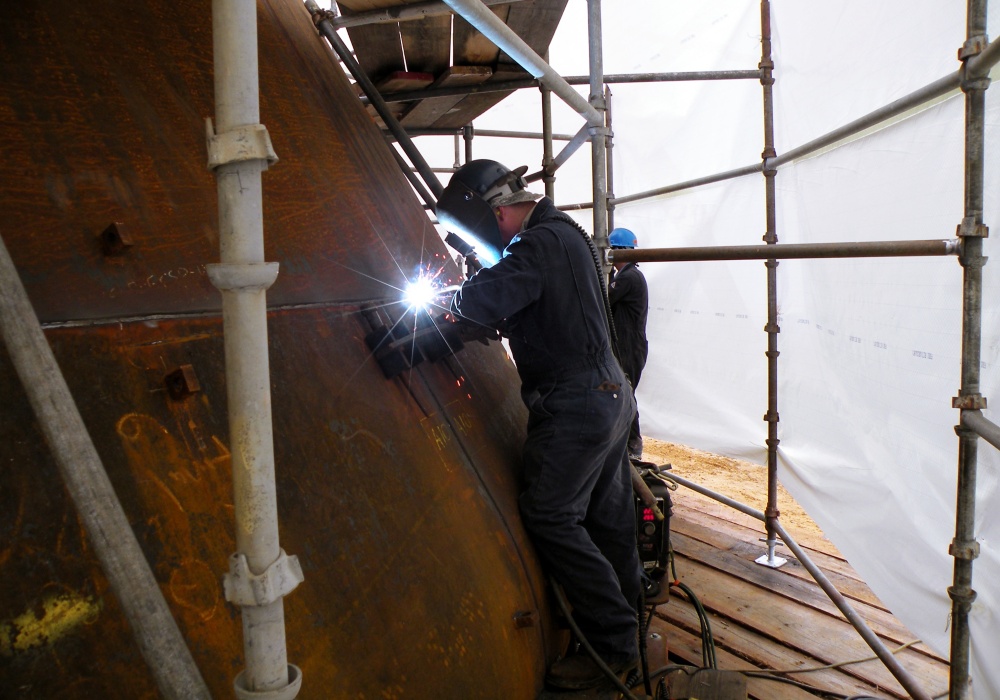 a group of people welding on a large metal structure