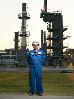 a man in a blue overalls standing in front of a factory