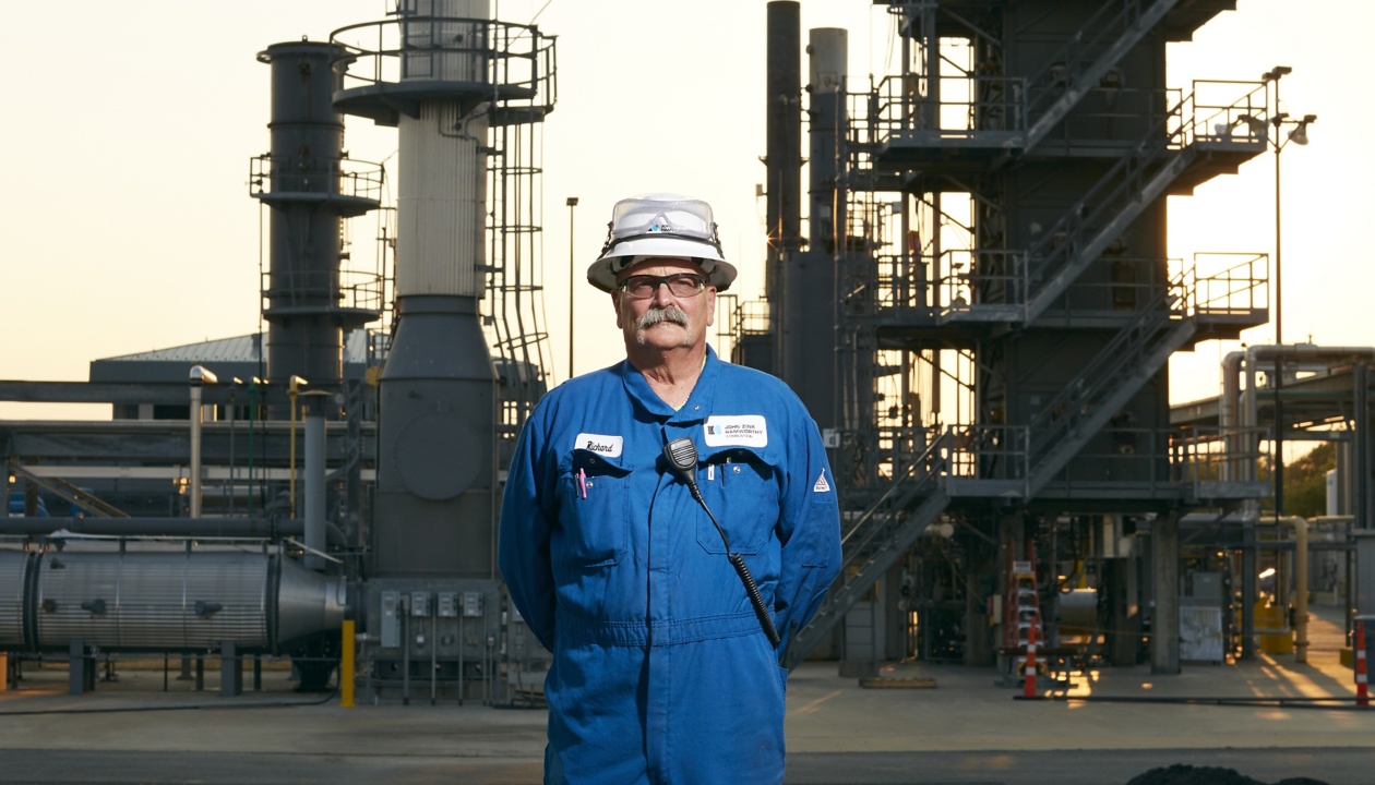 a man in a blue overalls standing in front of a factory