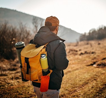 a man with a backpack walking in a field