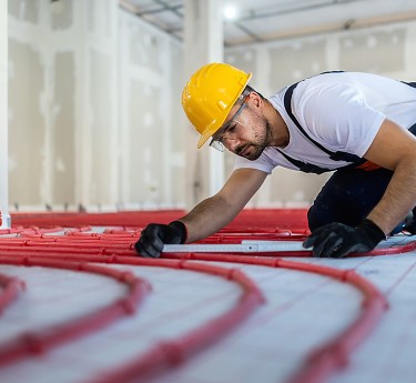 a man wearing a hard hat and gloves working on a floor