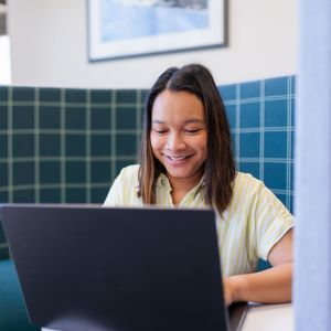 a woman smiling at a laptop