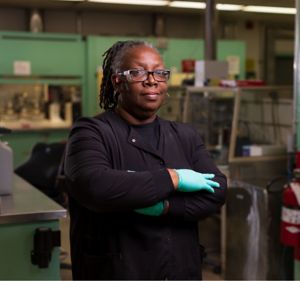 a woman wearing gloves and standing in a factory
