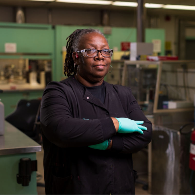 a woman wearing gloves and standing in a factory