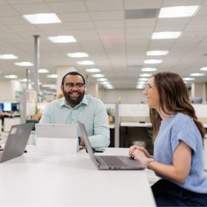 a group of people sitting at a table with laptops
