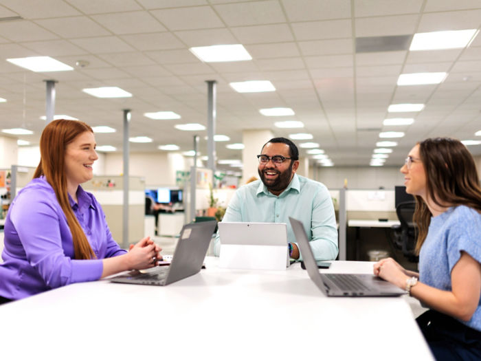 a group of people sitting at a table with laptops