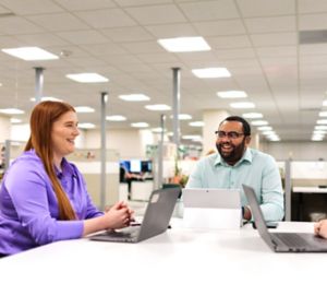a group of people sitting at a table with laptops