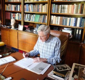 a man sitting at a desk writing on a book