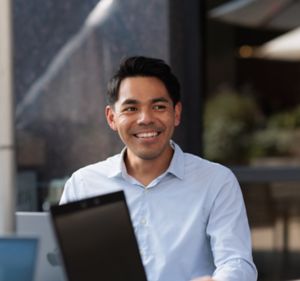 a man smiling and holding a laptop