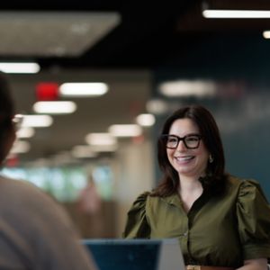 a woman in glasses talking to a man
