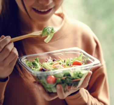 a woman holding a bowl of salad