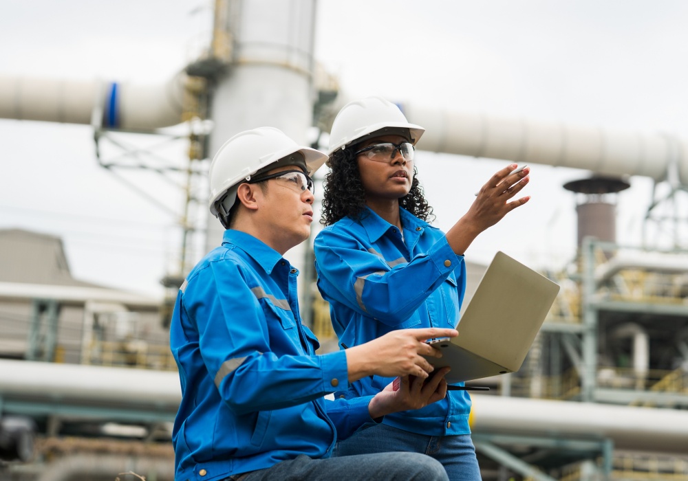 a man and woman wearing hardhats and holding a laptop